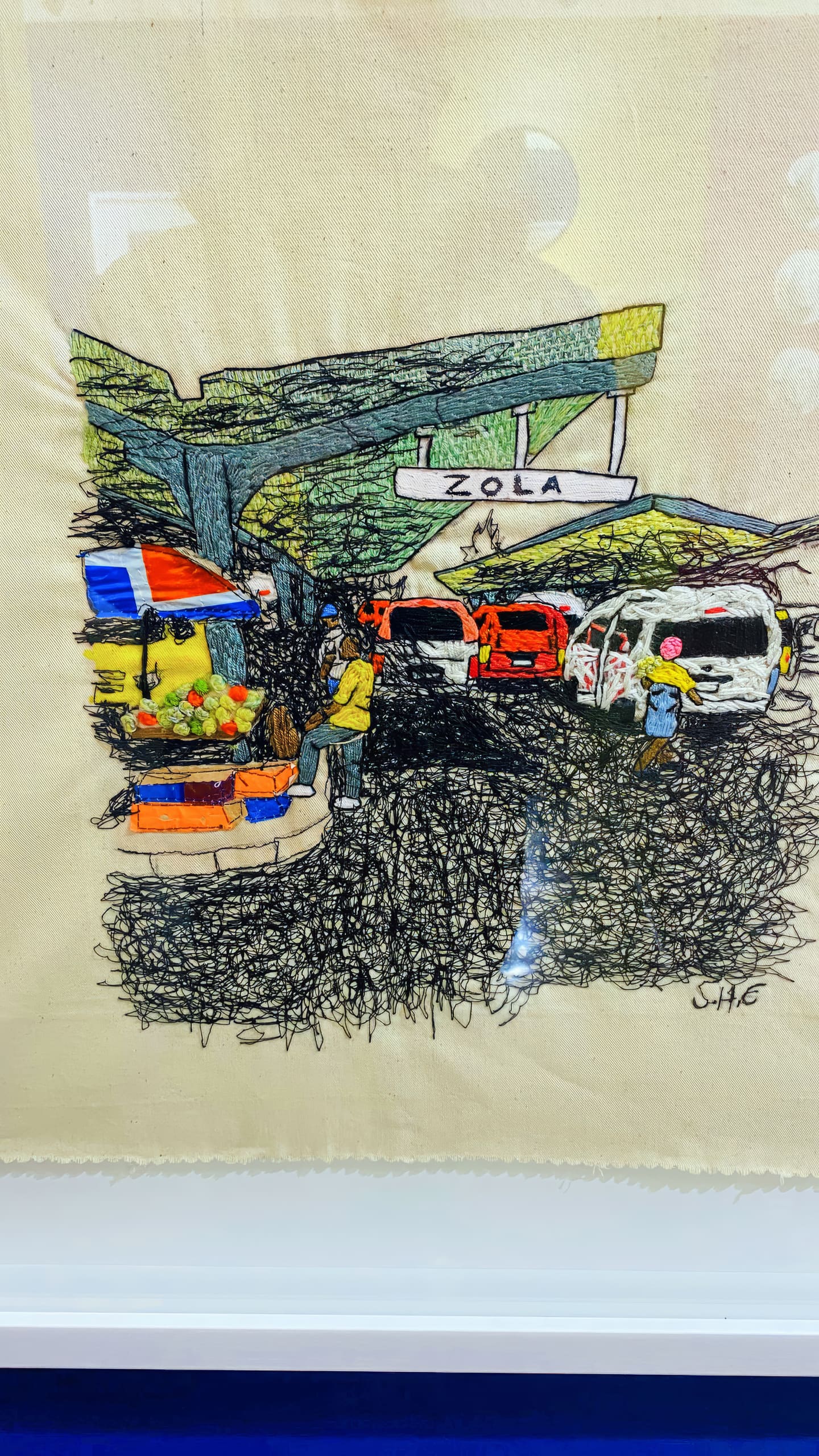 Embroidered artwork of a busy street scene at 