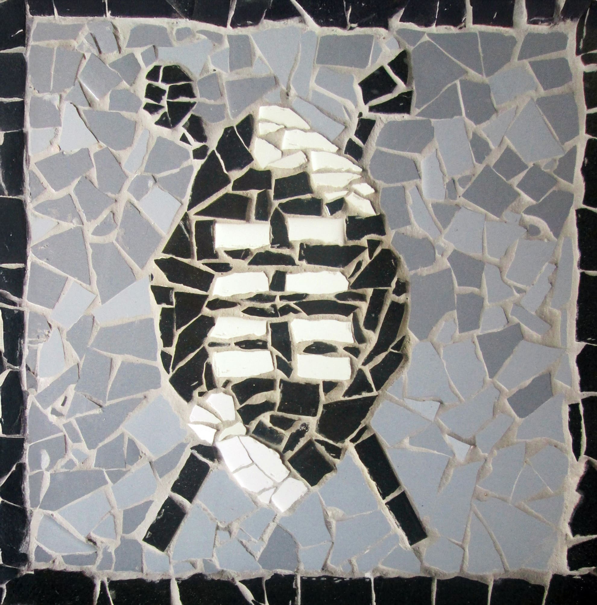 A mosaic shows two crossed oars behind a stylised shield. The background is made of light grey tiles, the oars are dark grey, and the shield is patterned with black and white tiles, resembling a rugby ball or similar sports emblem.