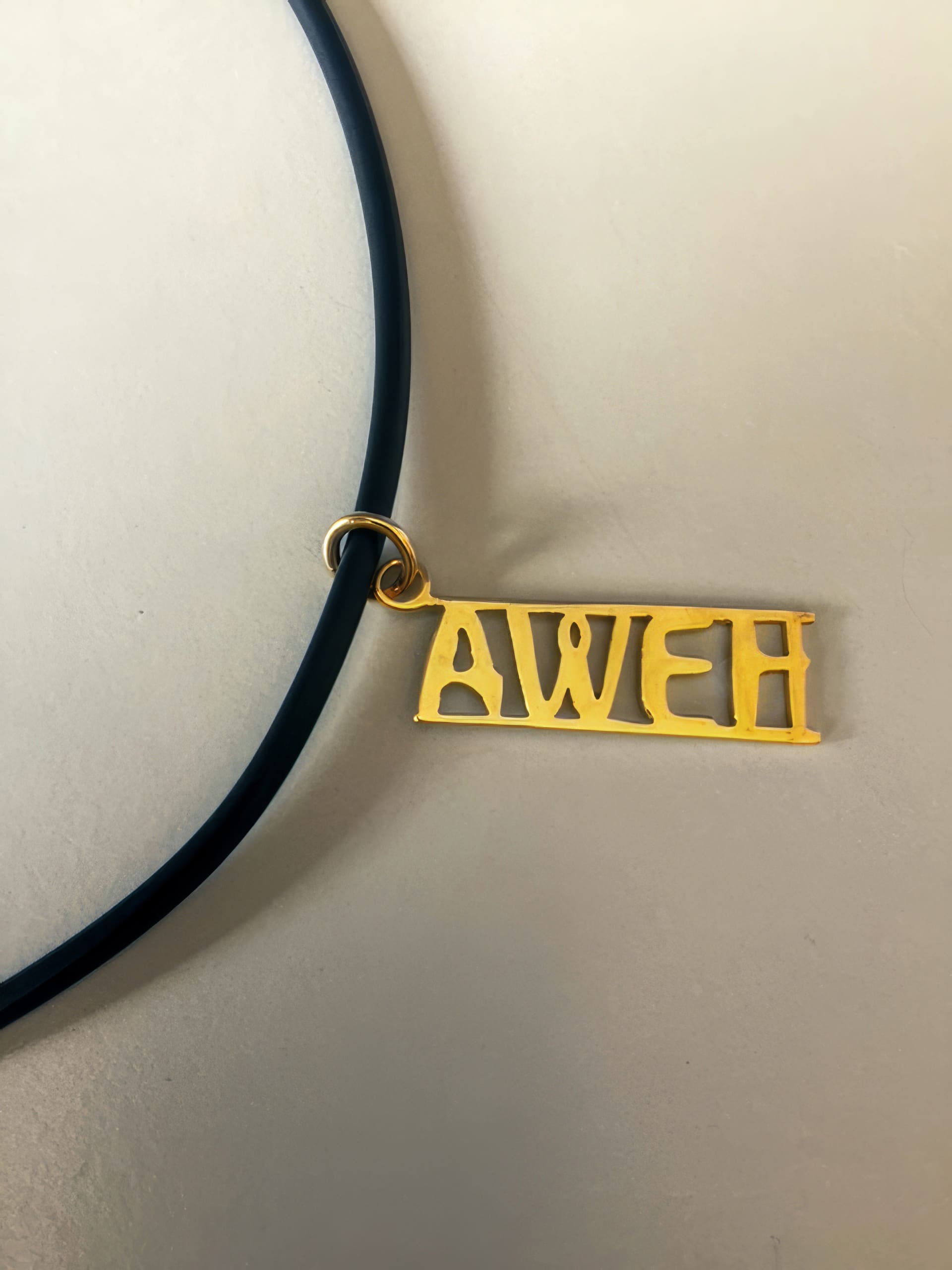 A gold rectangular pendant with the word 