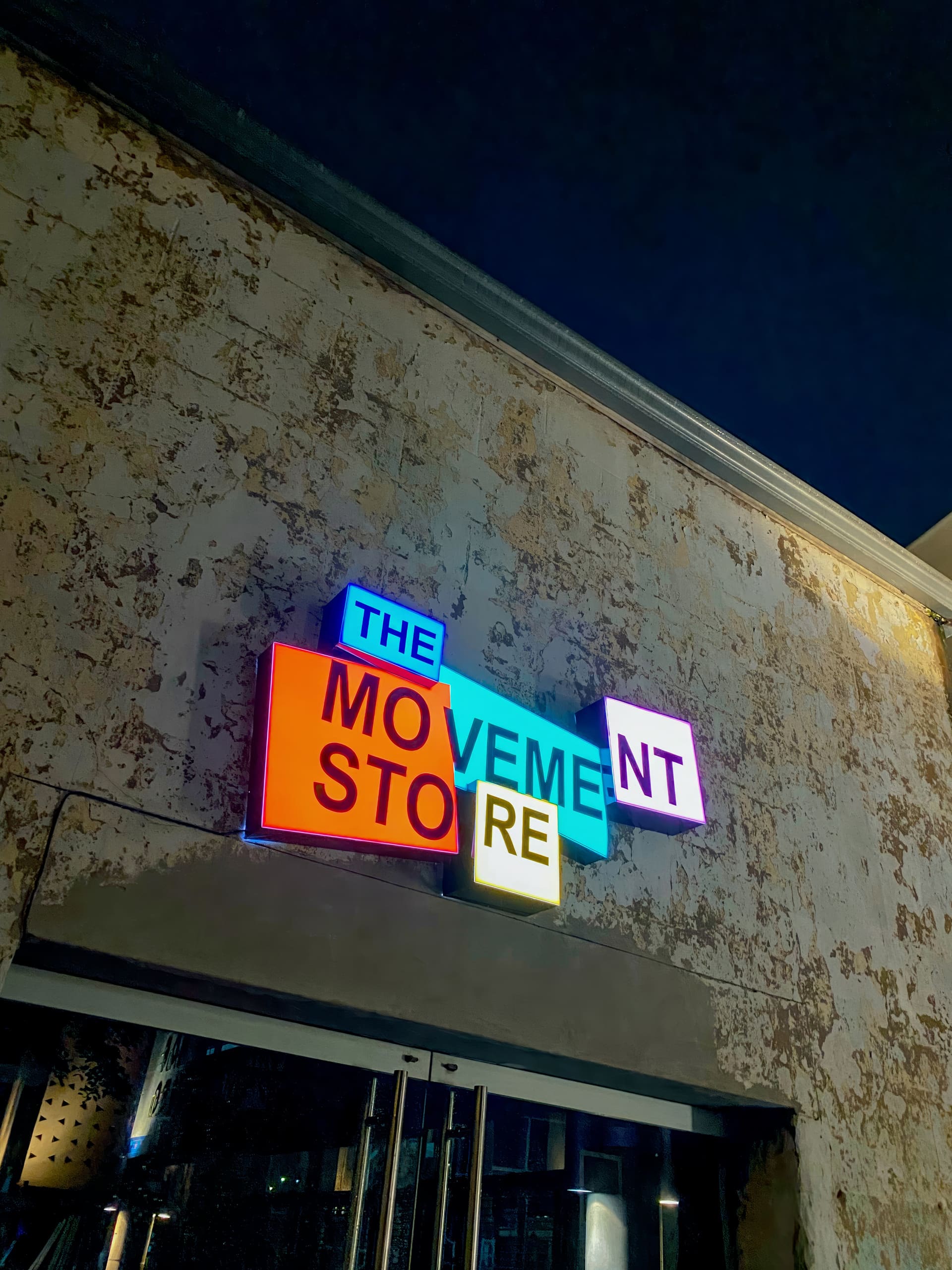 A neon sign on a weathered beige wall reads 