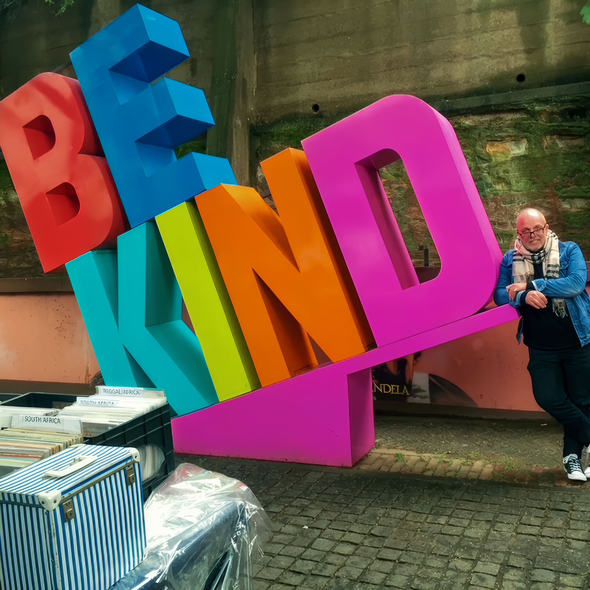 A cheerful person stands next to large, colourful 3D letters spelling 