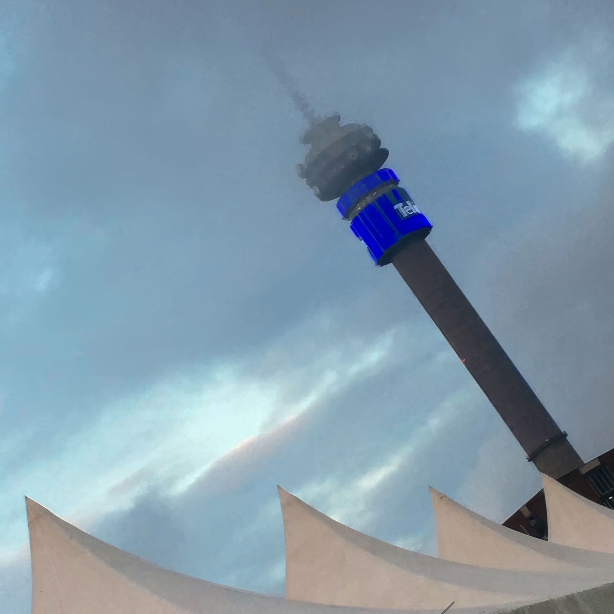 A tall communications tower rises into a cloudy sky, partly shrouded in mist. A blue illuminated sign wraps around the tower near the top. In the foreground, sharp white peaks of a tent-like structure are visible. The atmosphere appears moody and overcast.