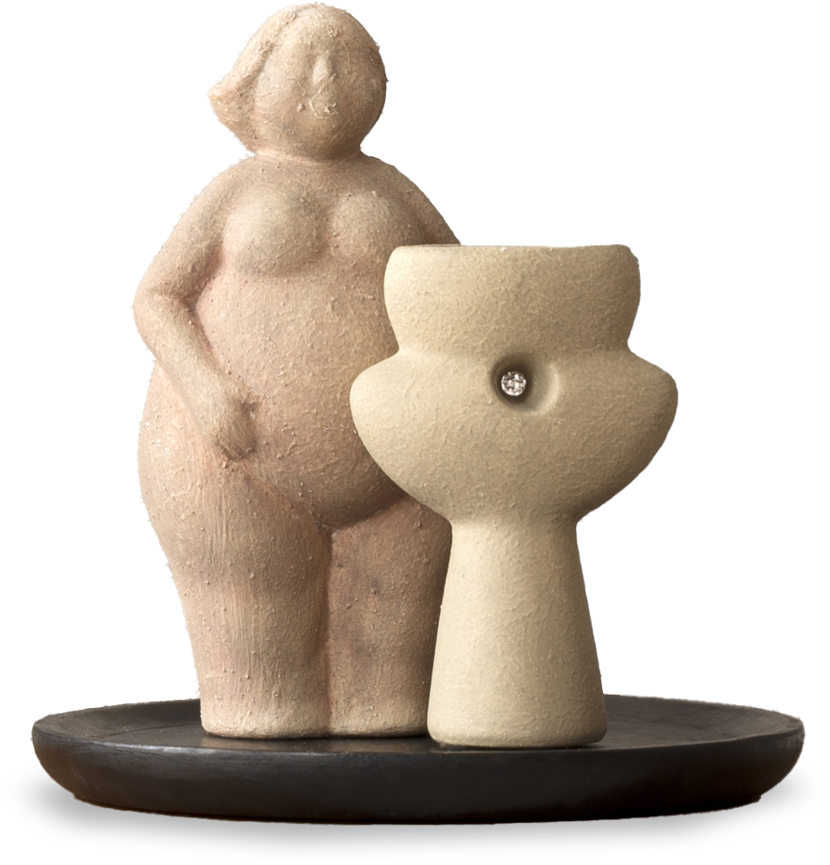 A clay figurine of a nude, full-bodied woman stands beside an abstract pedestal with a gem embedded in its centre, both positioned on a round, dark base. The figures are textured and softly coloured, emphasising curves and simplicity.