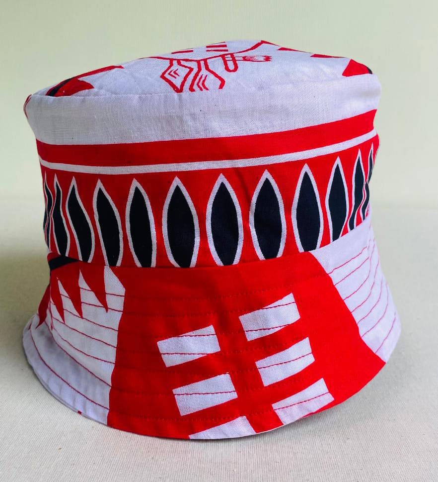 A colourful bucket hat featuring bold geometric patterns in red, white, and black. Inspired by Contra.Joburg, the design includes abstract motifs and vertical ovals, giving the hat a vibrant, striking appearance that captures the Weight of Silence.