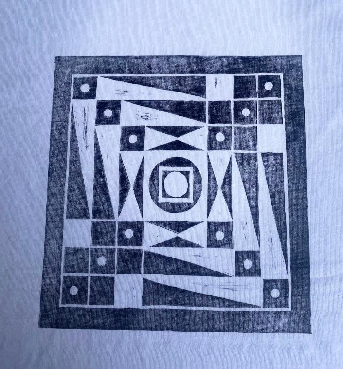 Black geometric print on white fabric showing a square filled with triangles, rectangles, circles, and a central concentric square pattern. The bold, abstract design evokes a modernist feel reminiscent of Contra.Joburg’s Weight of Silence.