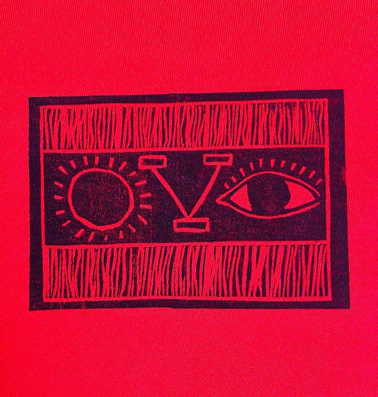 A rectangular black design on a red background—bold and abstract in style—features a sun on the left, a large 