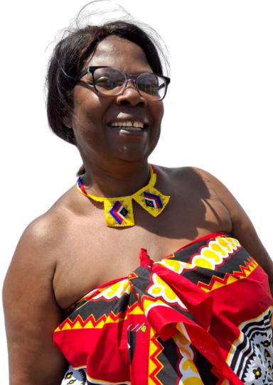 A smiling woman with short dark hair and glasses wears a colourful patterned cloth, reminiscent of Contra.Joburg style, wrapped around her body and a beaded necklace. The fabric features red, yellow, black, and white geometric designs against a plain white background.